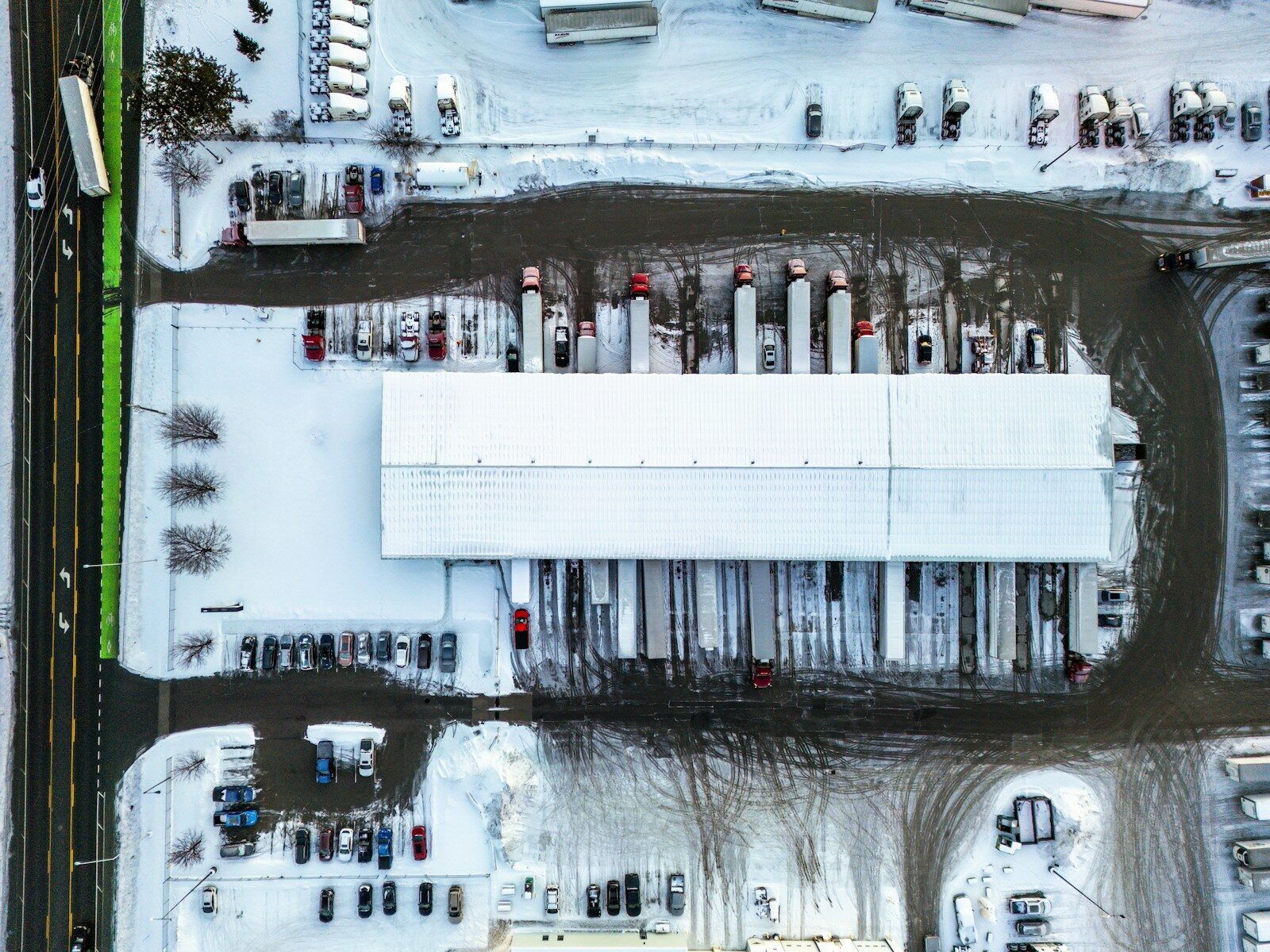 Aerial view of a snow-covered distribution center with trucks backed up to its loading docks