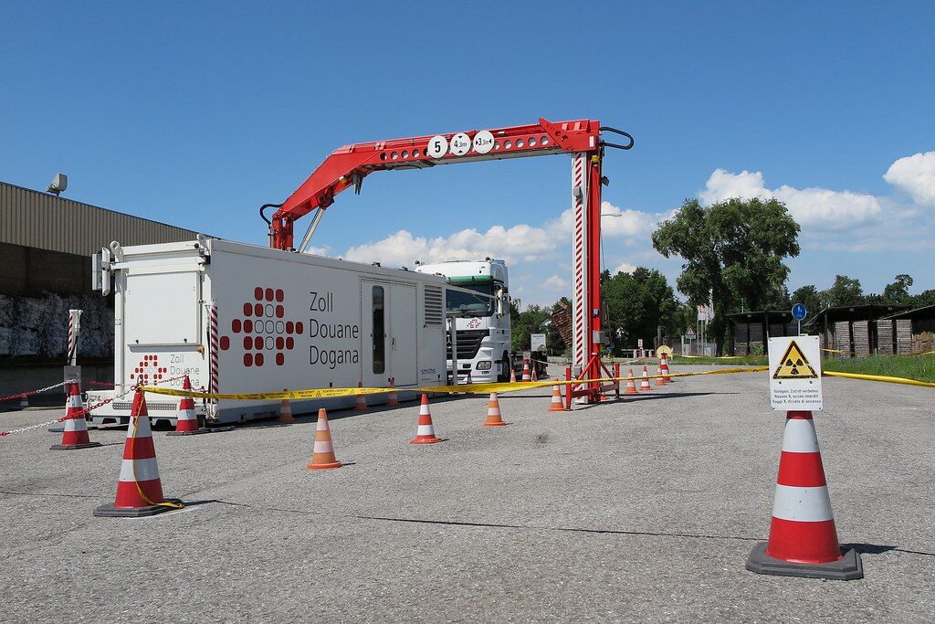 Truck waiting at a customs checkpoint beneath a mobile X-ray cargo scanning gantry