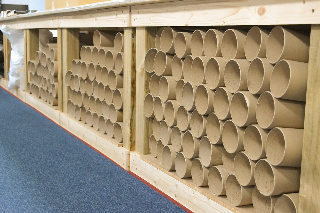 Rows of cardboard mailing tubes stacked on shelving in a storage room