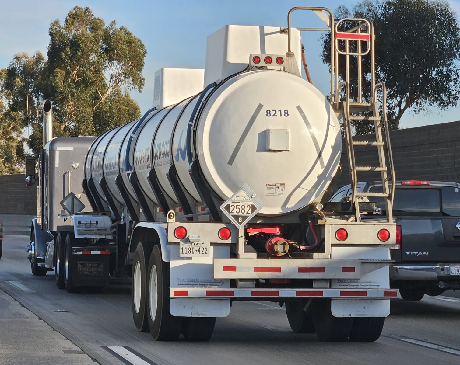 Tanker truck on a highway displaying a hazardous materials placard for class 8 corrosive cargo