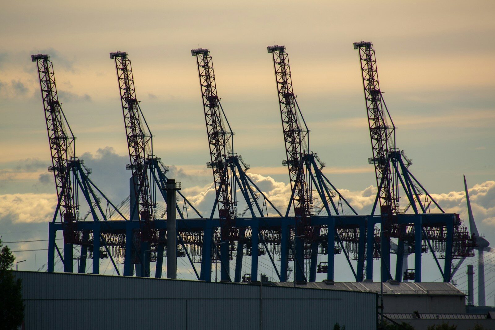 Row of ship-to-shore container cranes against a cloudy evening sky