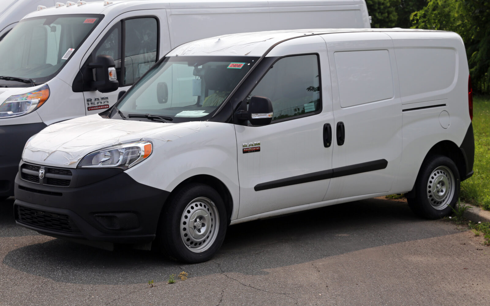 Plain white compact cargo van parked beside a larger van