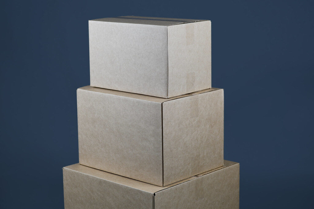Three taped cardboard parcels of different sizes stacked against a dark blue background